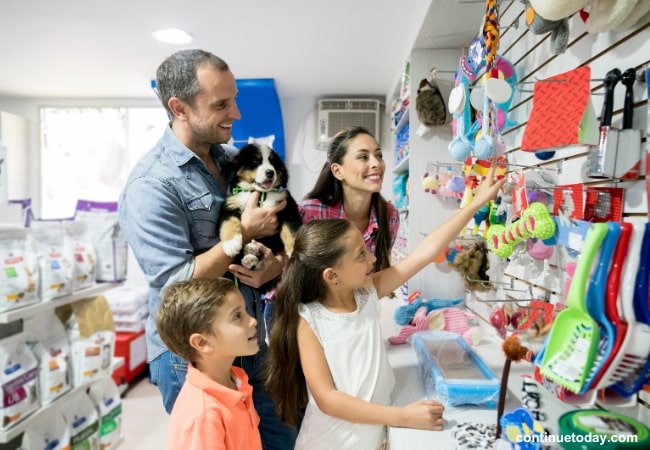 A family of four with a pet dog choosing pet supplies in a pet store