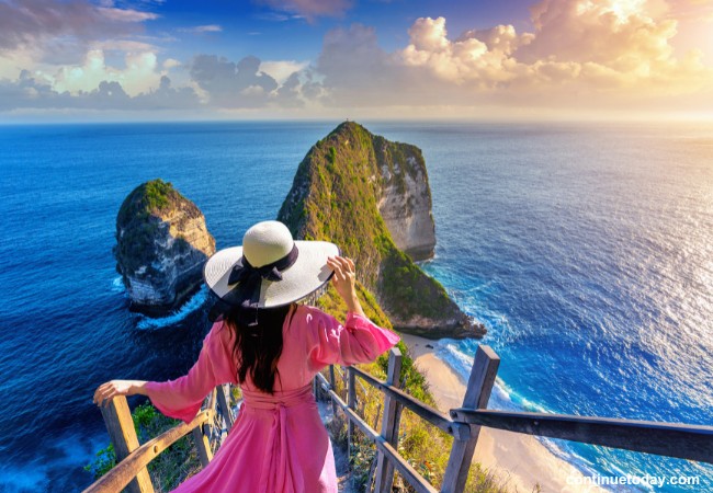A girl is holding her hat and enjoying the view