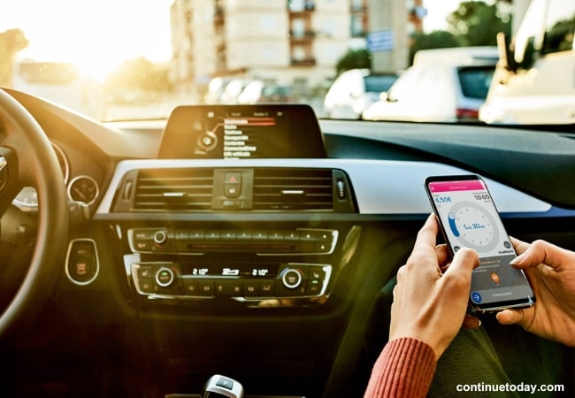 hand holding a mobile to operate IoT Projects in Automotive